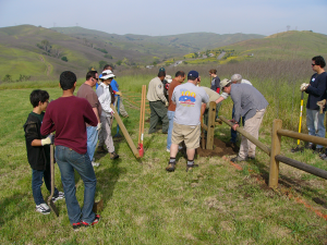 Volunteers help park staff build fencing around a group campground.